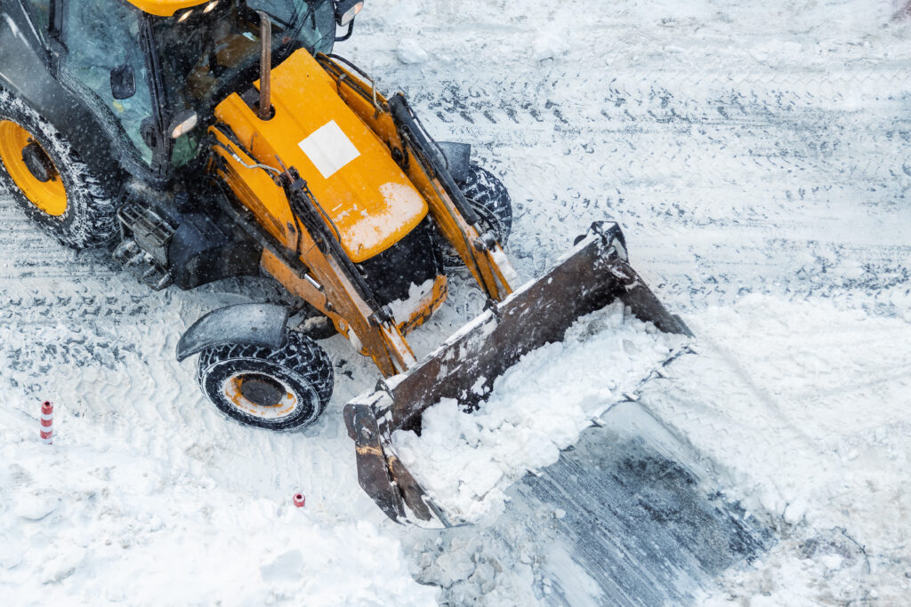 Front-end loader clearing snow from a commercial property during a winter storm.