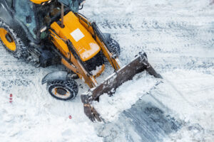 Front-end loader clearing snow from a commercial property during a winter storm.