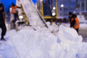 Snow removal crew clearing heavy snow with machinery during a winter storm.
